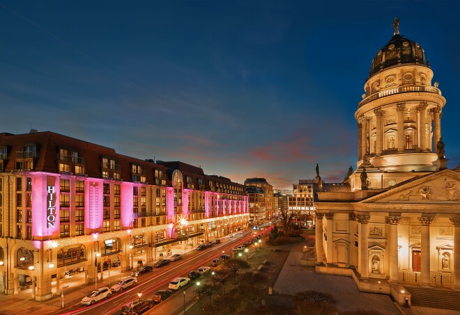 Pink lights shining on the facade of Mitte’s Hilton Berlin at dusk.