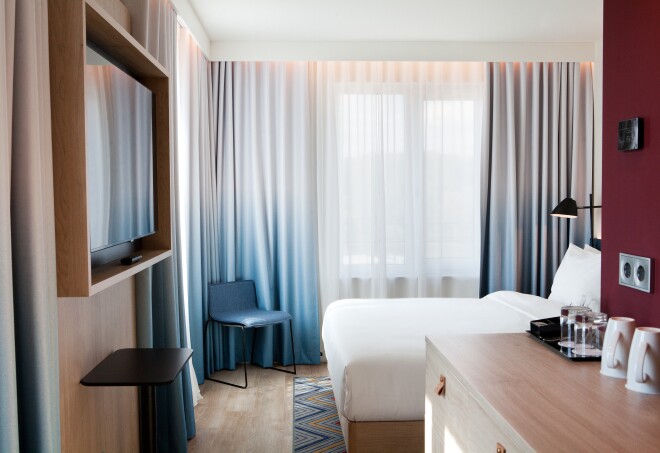 A guest room with curtains drawn at Hampton by Hilton Regensburg, Germany