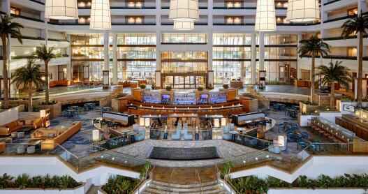 The large and airy central lobby at the JW Marriott Desert Springs Resort and Spa with huge hanging chandeliers, a central bar and palm trees around it