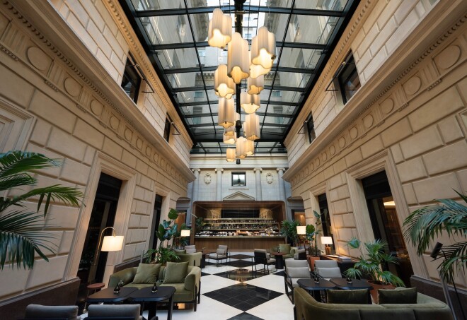 View of the lobby bar at Hotel Casa Lucia in Buenos Aire. the floor is checkered black and white and the ceiling is a glass roof with a chandelier