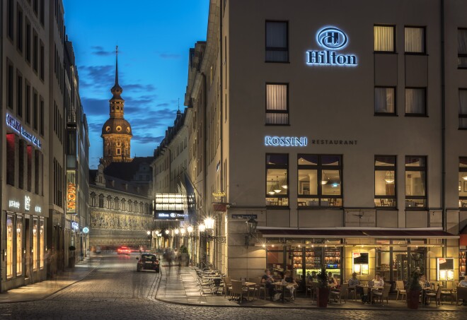 A photograph of the exterior of the Hilton Dresden at night in Dresden, Germany