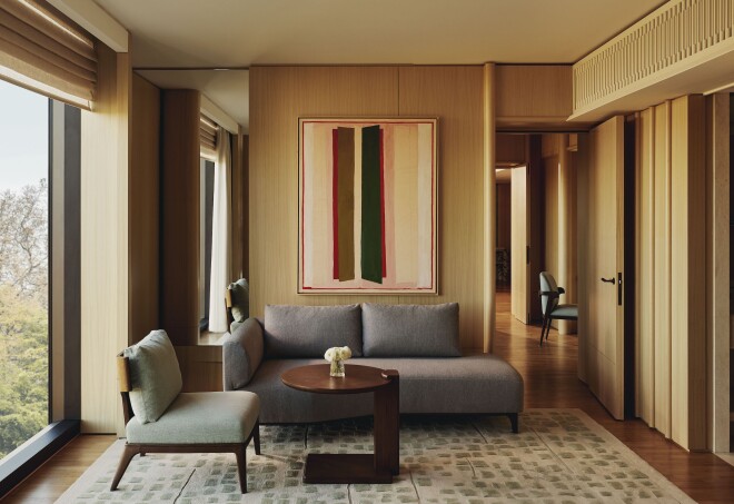 This suite designed by Andre Fu at the Emory Hotel features large gray seating, blond wood walls, and floor-to-ceiling windows.